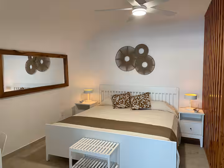 Recámara con cama matrimonial y ventilador