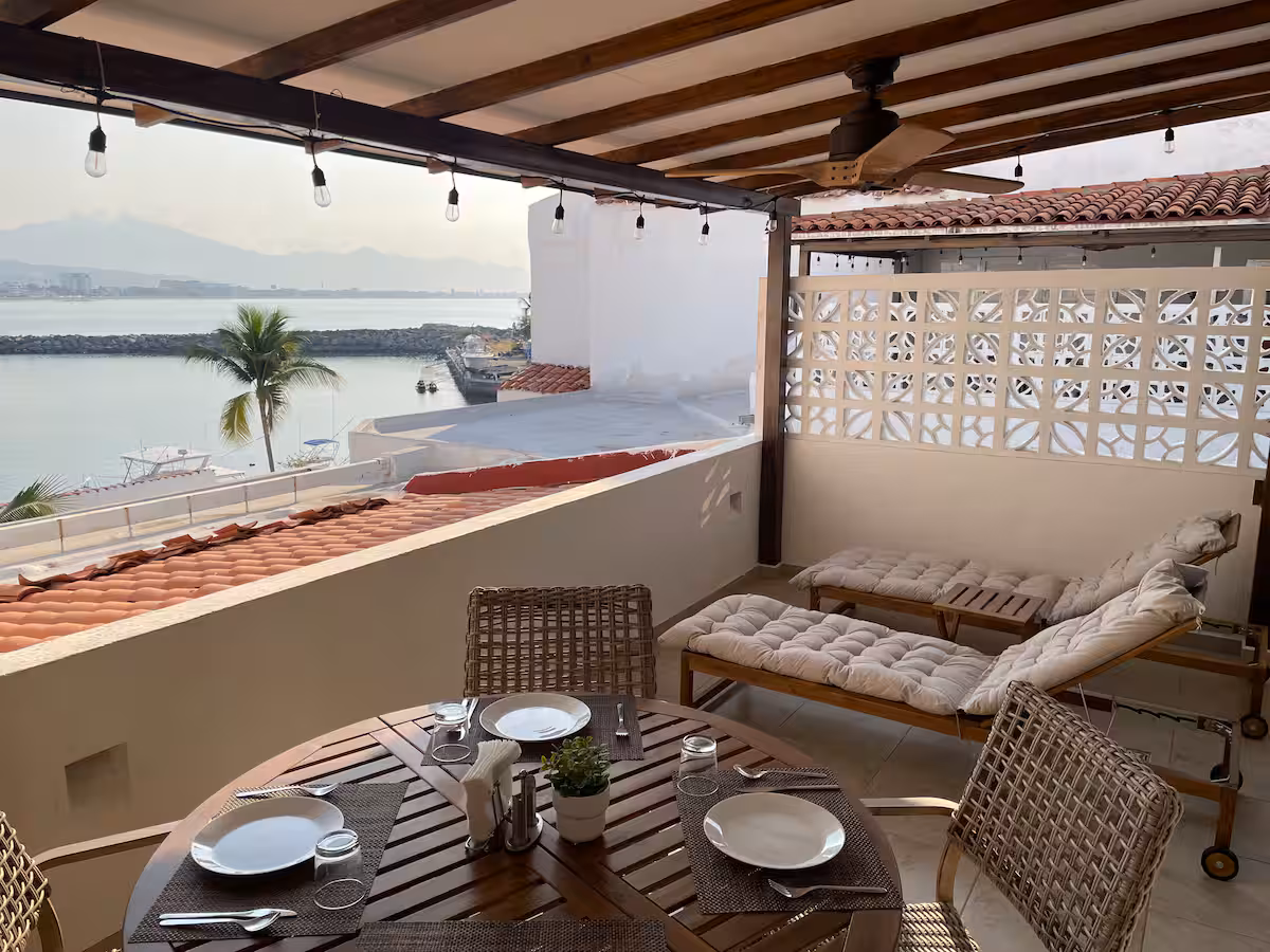 Terraza con mesa, camastros y vista a la bahía